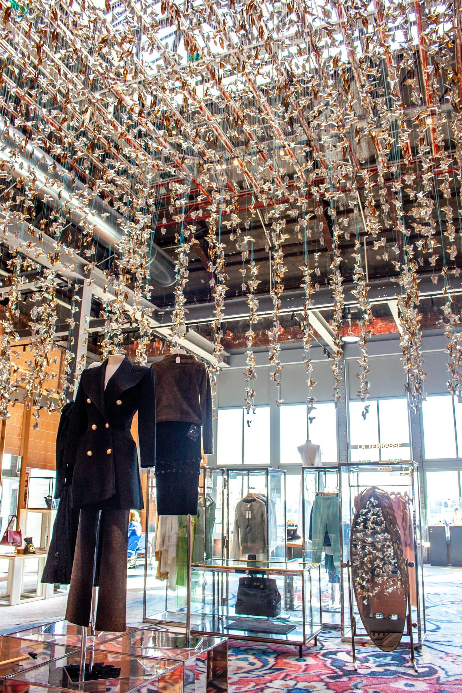 Intérieur de boutique de mode haut de gamme sous une installation suspendue dorée.