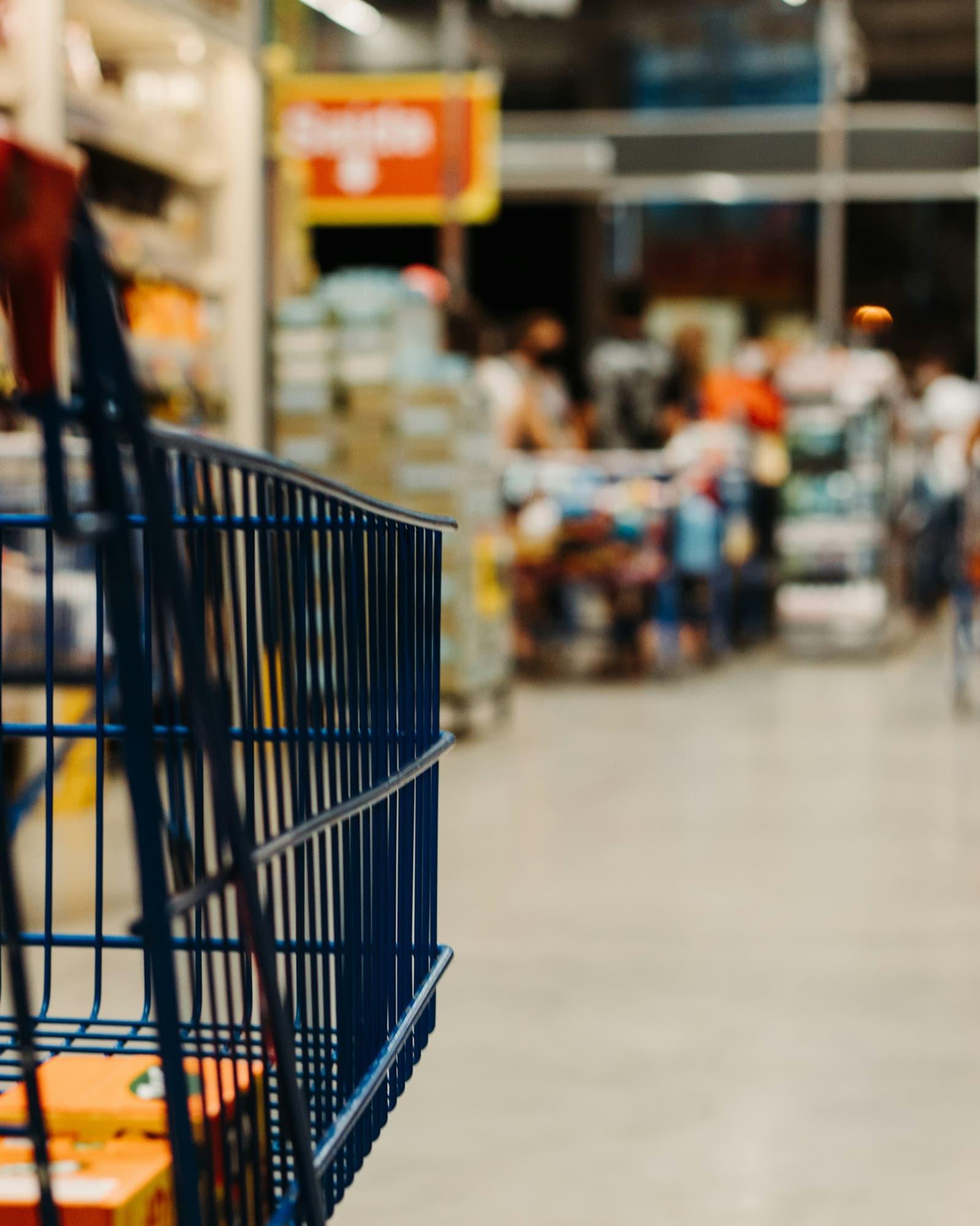 Chariot de supermarché dans une allée, l'arrière-plan en flou.
