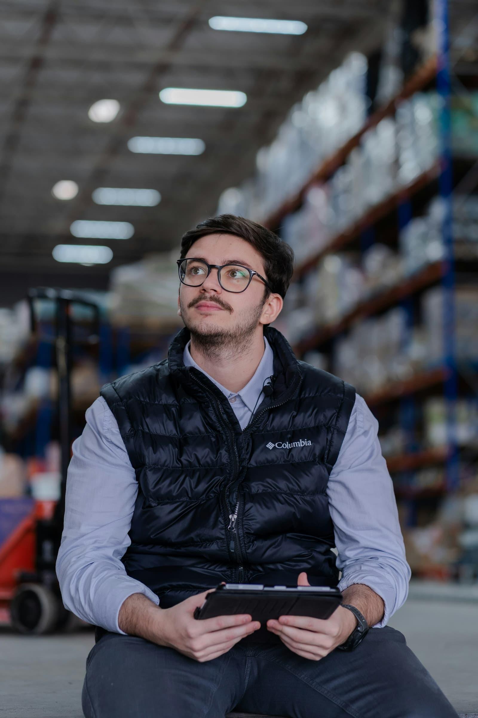 Gestionnaire de stock consultant une tablette au milieu d'un entrepôt.