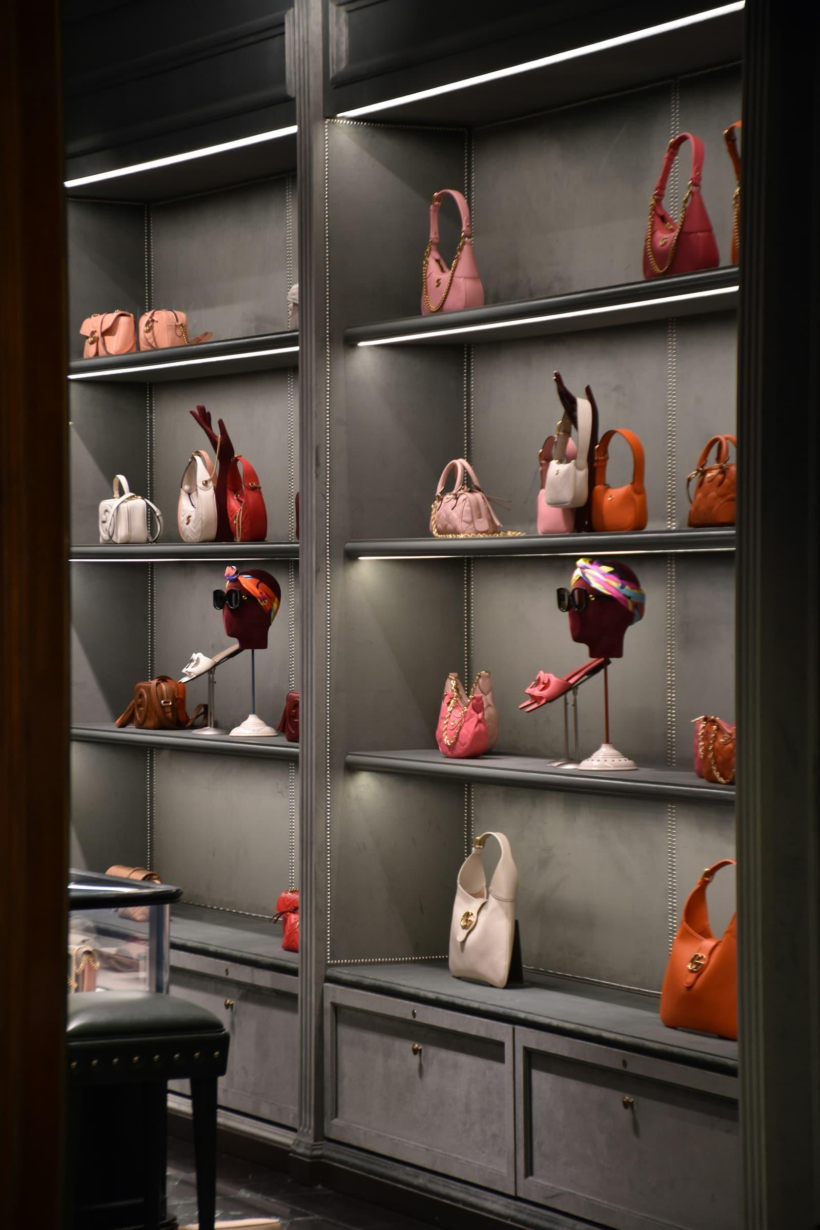 Présentoir de maroquinerie de luxe, sacs disposés sur des étagères éclairées.