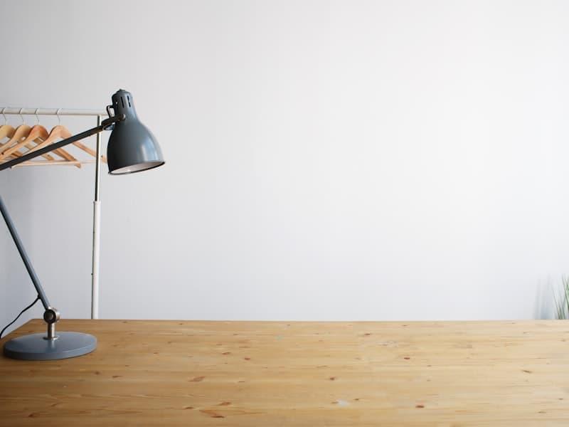 Lampe d'architecte grise posée sur un plan de travail en bois.