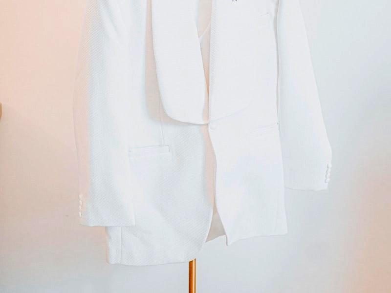 Veste de costume claire suspendue à un cintre.