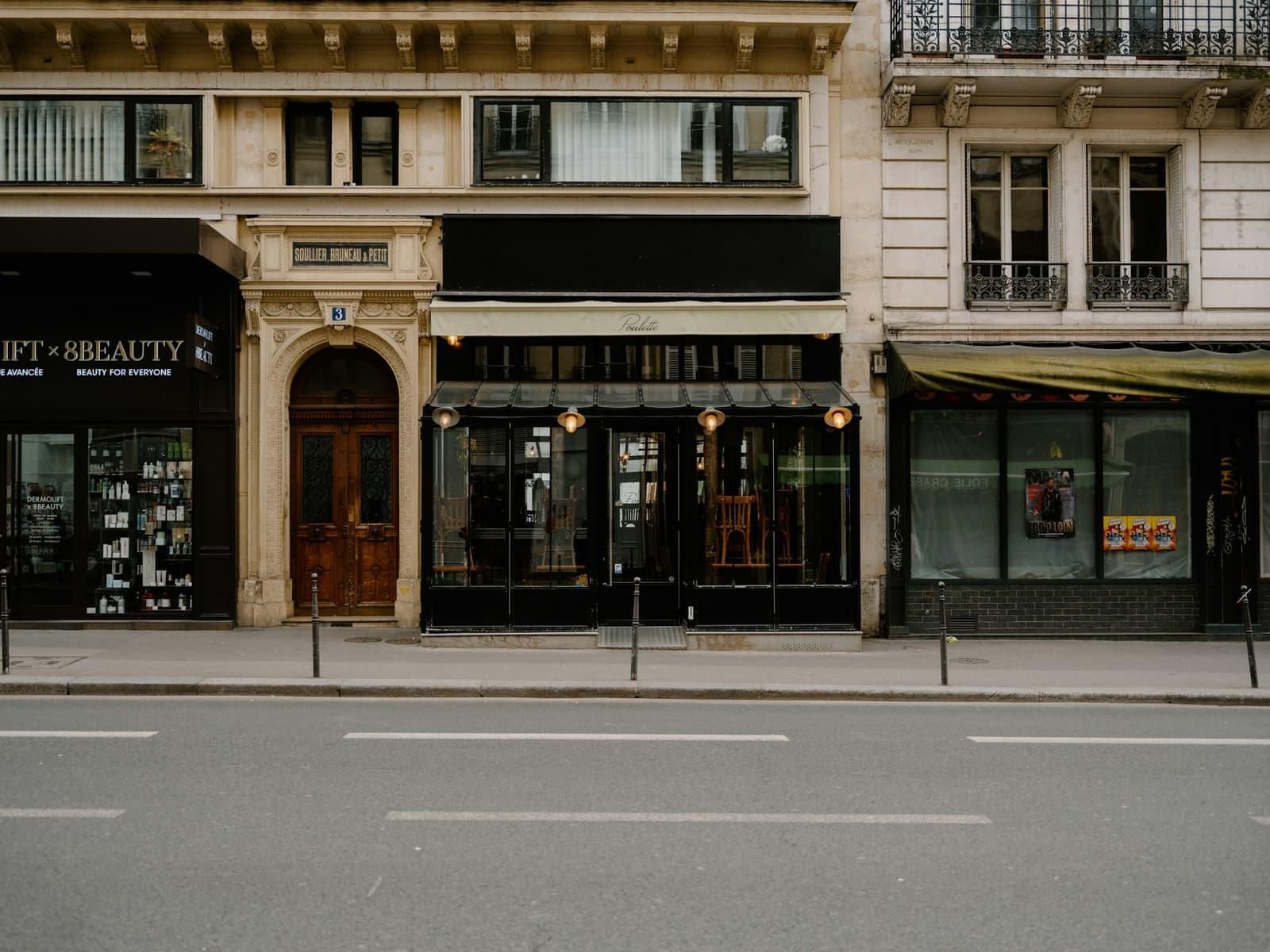 Alignement de commerces au rez-de-chaussée d'un immeuble haussmannien.