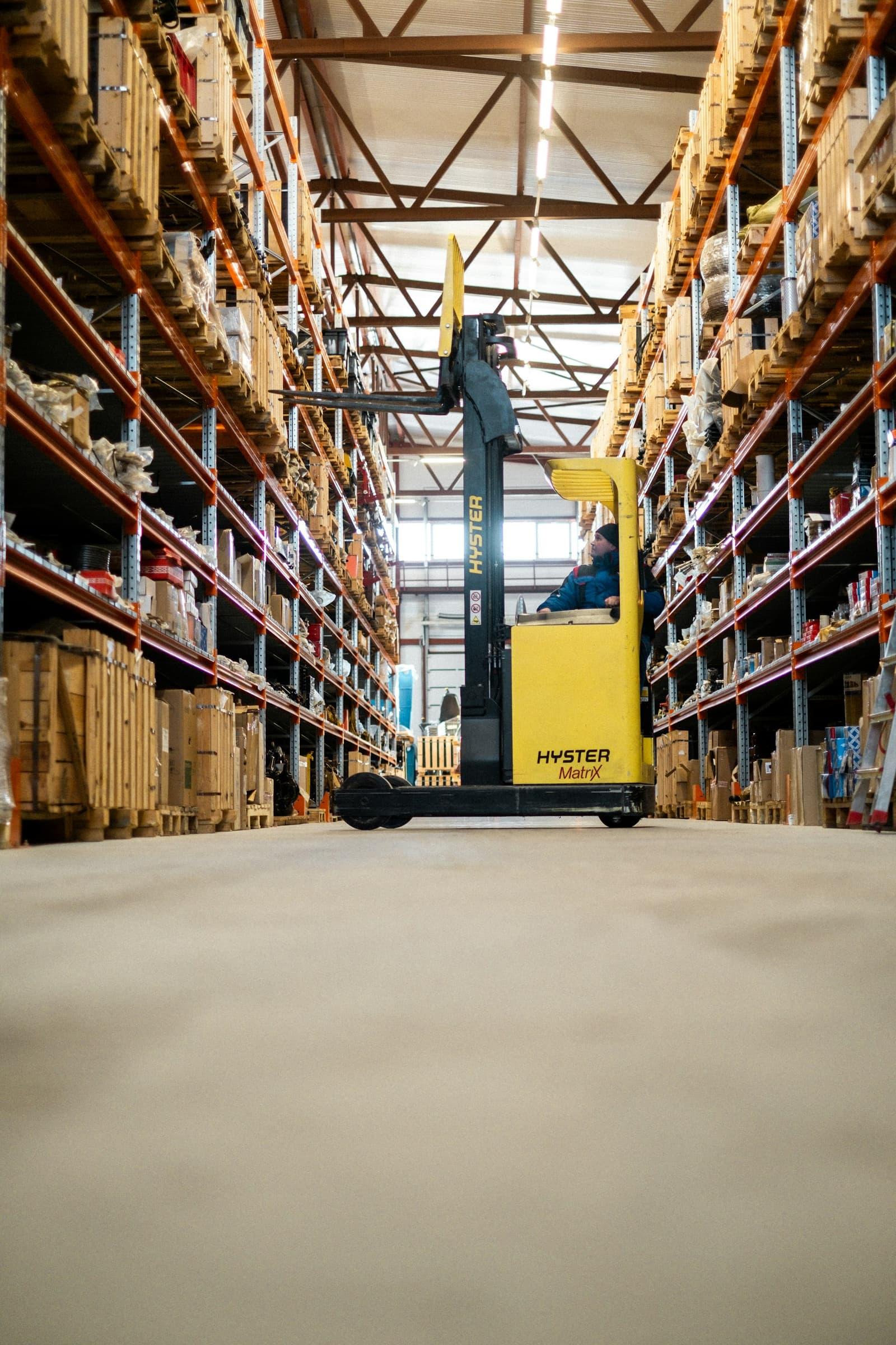 Chariot élévateur jaune dans une halle logistique.
