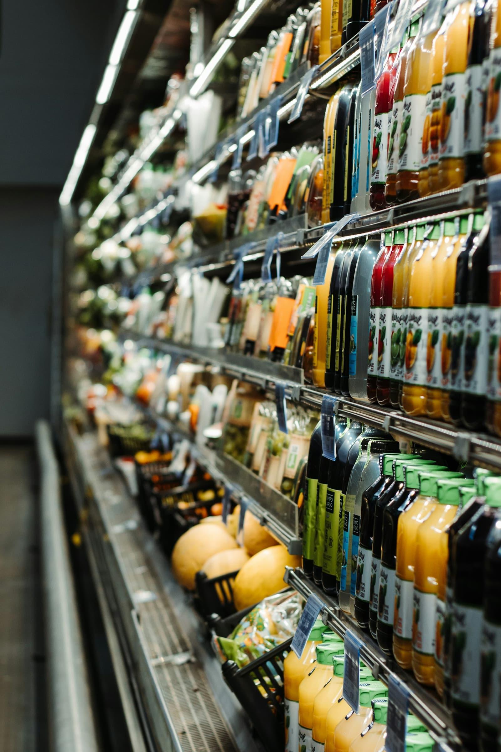 Rayon réfrigéré d'un magasin alimentaire, bouteilles et produits frais alignés.
