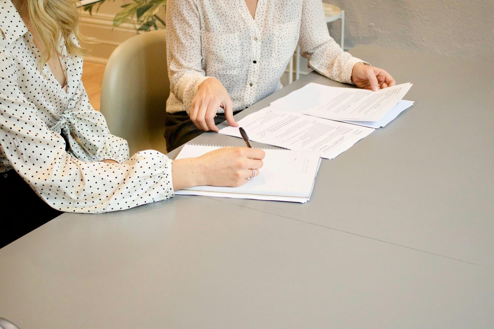 Deux personnes parcourant un contrat imprimé sur une table.