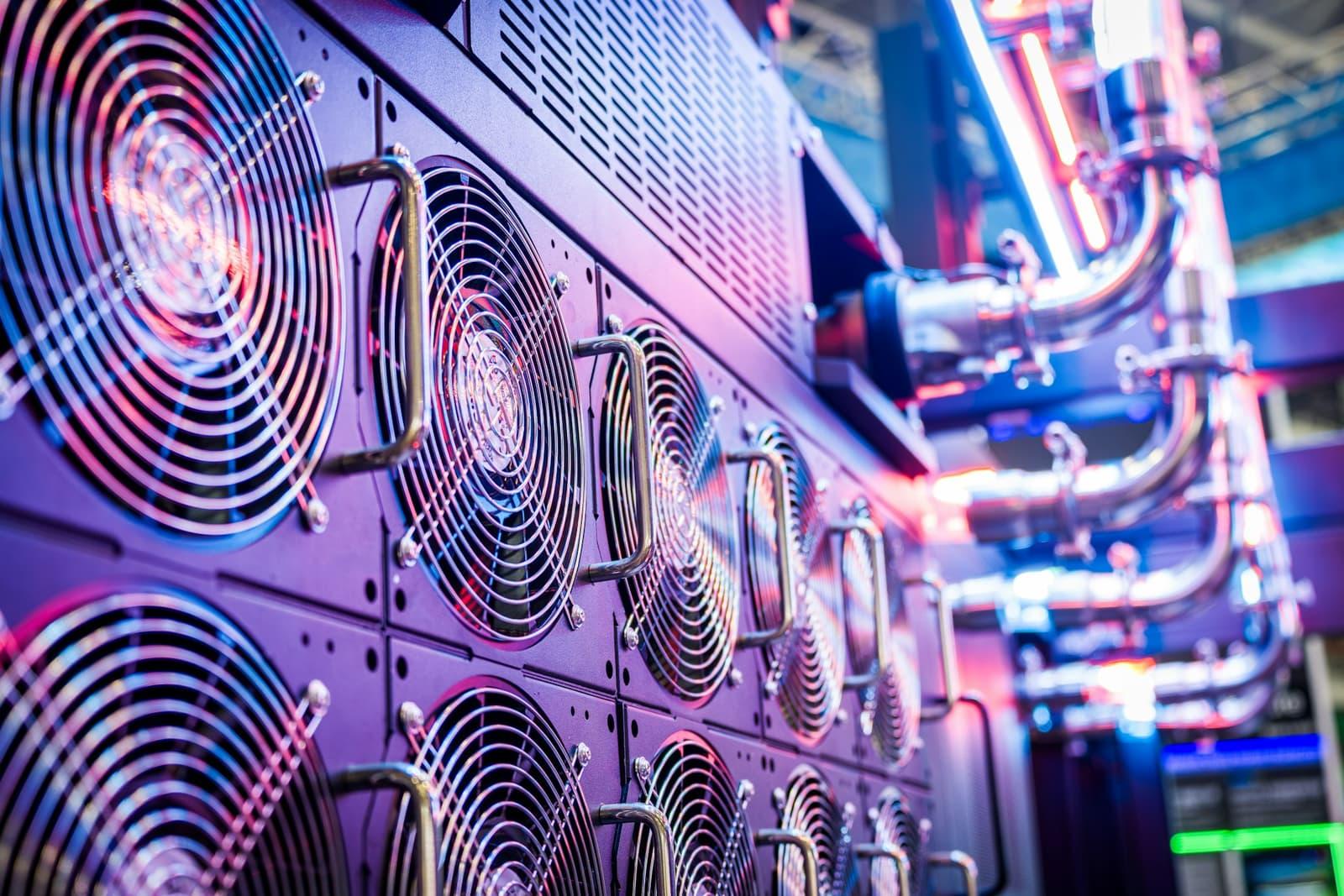 Mur de ventilateurs et de tuyauteries de refroidissement en salle technique.